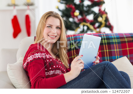 Pretty girl lying on sofa using her tablet smiling at camera Pretty girl lying on sofa using her tablet smiling at camera 12472207