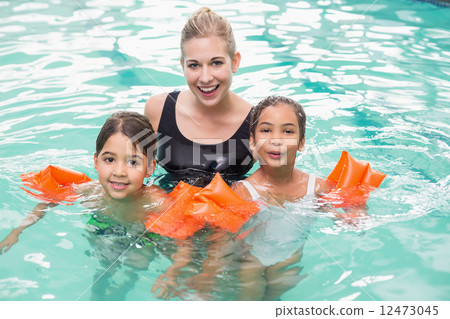 Cute swimming class in pool with coach Cute swimming class in pool with coach 12473045