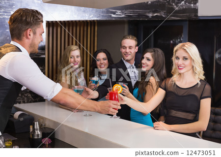 Attractive friends being served cocktails Attractive friends being served cocktails 12473051