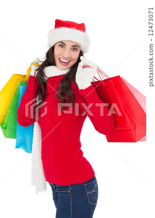 Festive brunette in winter wear holding shopping bags 12473071