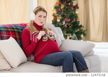 Smiling pregnant woman with baby shoes on her belly 12473138