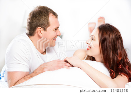 Young man and woman lying together in bed 12481358