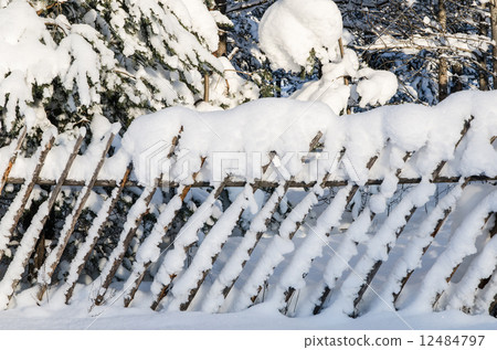 The wooden fence filled up by a snow in a countryside. 12484797