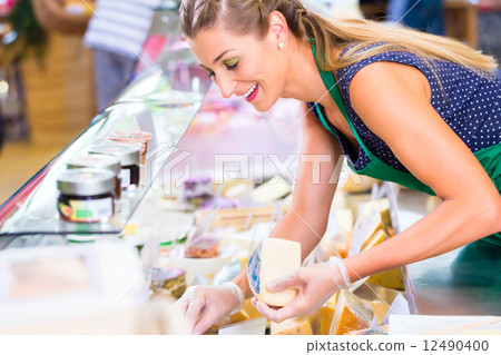 Saleswoman working at counter in groceries shop 12490400