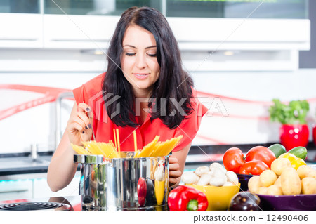 Woman cooking pasta in domestic kitchen Woman cooking pasta in domestic kitchen 12490406