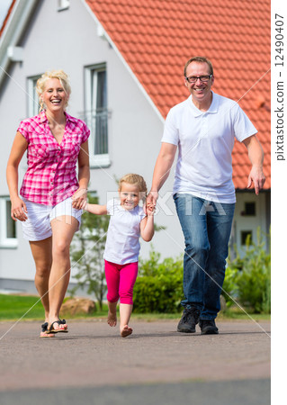 Family taking walk in front of home Family taking walk in front of home 12490407