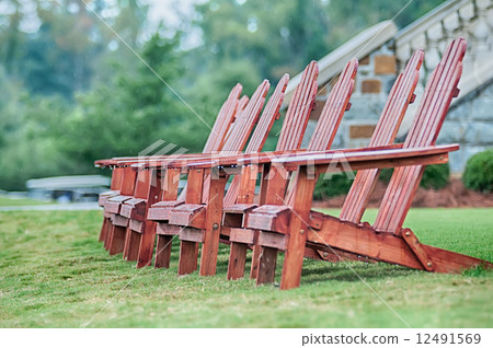 Two wooden adirondack chairs on lush green lawn 12491569