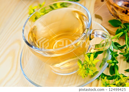 Tea from tutsan in glass cup on board with flowers Tea from tutsan in glass cup on board with flowers 12499425