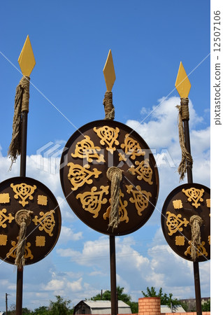 Oriental shields with gilded decoration hanging on decorative spears Oriental shields with gilded decoration hanging on decorative spears 12507106