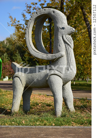 Stone statue featuring a wether with big horns- in the park of Astana, Kazakhstan 12507112