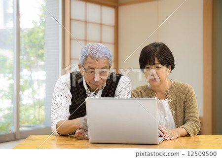 諮詢資深的夫婦，當觀看個人計算機在日本式屋子裡時 12509500