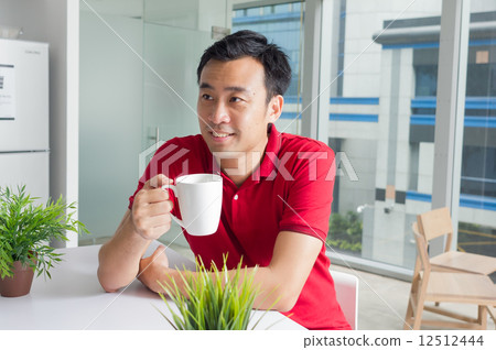 A young Asian middle-age adult enjoying a cup of tea / coffee in a cafe 12512444