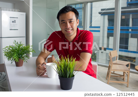 A young relaxed Asian middle-age adult enjoying a cup of tea / coffee in a cafe 12512445