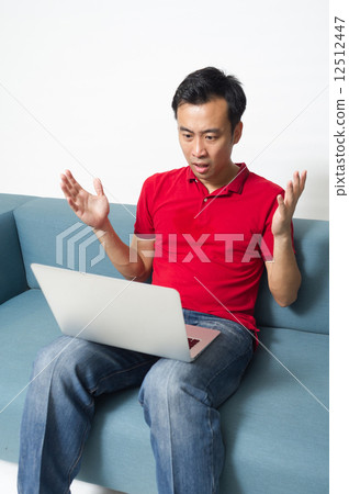 A middle-age Asian man in disbelief after leaning that he has lost his money to online gambling 12512447