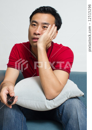 Middle-age Asian man is feeling bored while he sits on the sofa 12515296