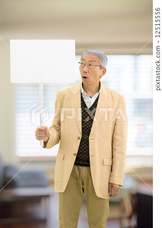 Senior men standing holding a placard in the living room 12515556