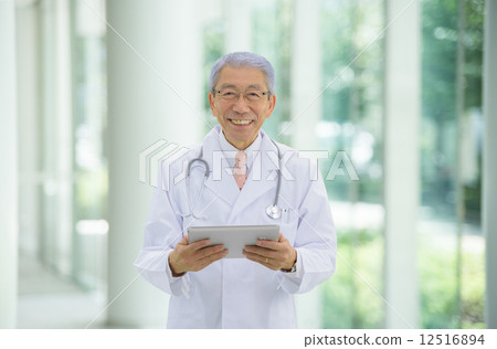 站立與在一家大醫院的入口的一種片劑的拉丁文的灰色醫生 12516894