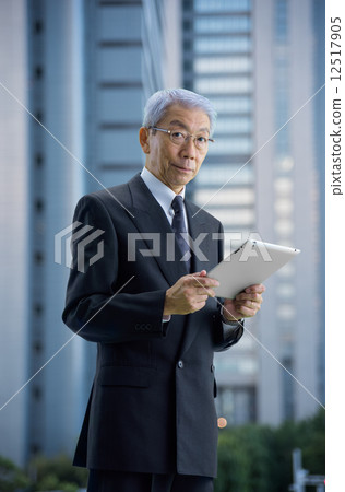 Executive to see the tablet in a skyscraper at dusk Executive to see the tablet in a skyscraper at dusk 12517905