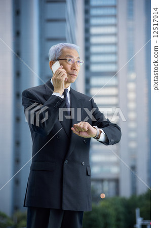 行政人員在黃昏時在摩天大樓打電話 12517914
