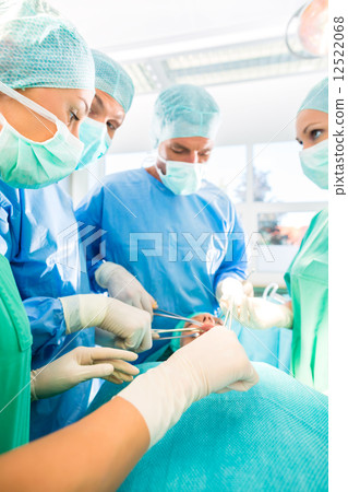 Surgeons operating patient in operating room 12522068