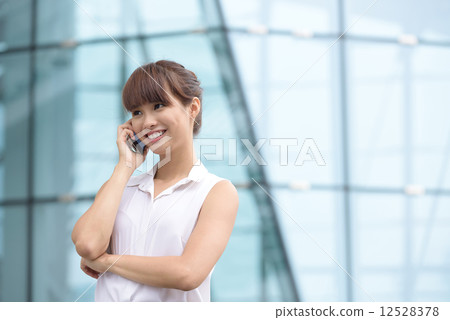 Young successful Chinese business woman making voice call in front of glass office building Young successful Chinese business woman making voice call in front of glass office building 12528378