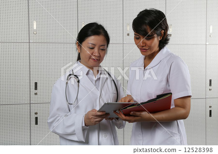 Lady doctor and nurse comparing notes. Lady doctor and nurse comparing notes. 12528398