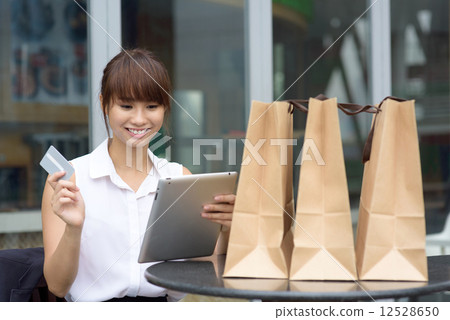 One young successful Chinese business woman shopping online with tablet iPad and credit card   12528650
