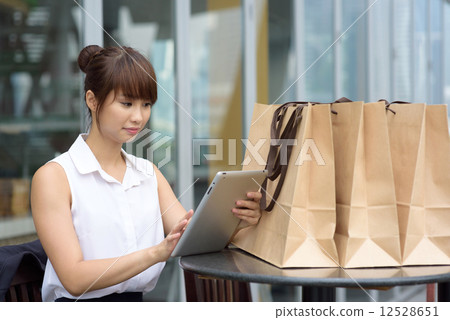 One young successful Chinese business woman shopping online with tablet iPad along promenade   12528651