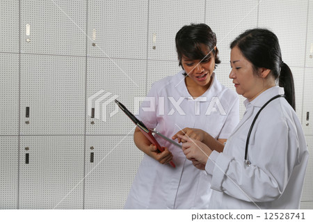Nurse highlighting a point to lady doctor. Nurse highlighting a point to lady doctor. 12528741