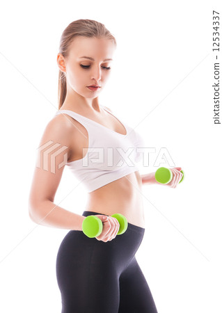 Athletic woman pumping up muscles with dumbbells Athletic woman pumping up muscles with dumbbells 12534337
