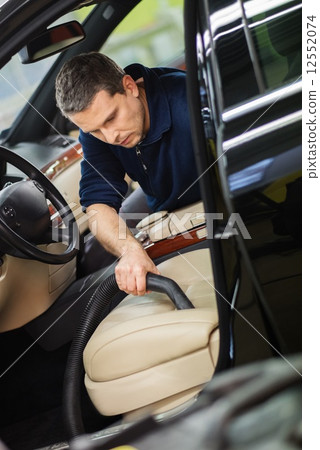 Worker on a car wash cleaning car interior with vacuum cleaner Worker on a car wash cleaning car interior with vacuum cleaner 12552074