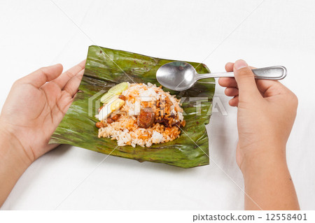 Simple and original traditional nasi lemak wrapped in banana leaf being consumed. 12558401