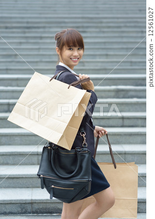One young Chinese office lady carrying shopping bags in front of steps One young Chinese office lady carrying shopping bags in front of steps 12561027
