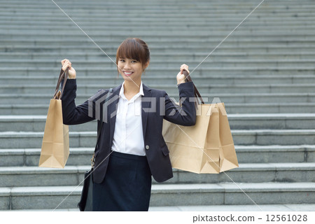 One young Chinese office lady carrying shopping bags in front of steps 12561028