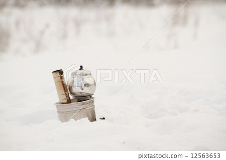 Portable stove in a picnic field covered with snow Portable stove in a picnic field covered with snow 12563653