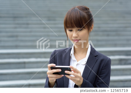 One young Chinese office lady using smart phone in front of steps One young Chinese office lady using smart phone in front of steps 12565719