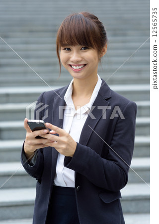 One young Chinese office lady using smart phone in front of steps 12565735