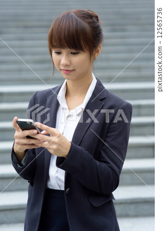 One young Chinese office lady using smart phone in front of steps 12565736
