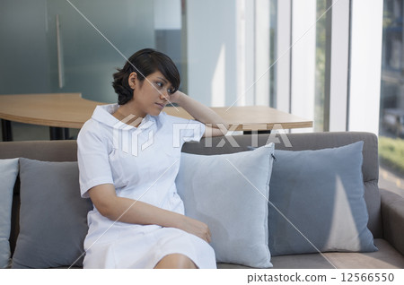 Young Asian nurse coming down with a migraine. 12566550