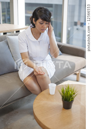 Young Asian nurse coming down with a migraine. Young Asian nurse coming down with a migraine. 12566553