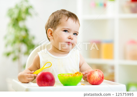 displeased kid boy with healthy food at kitchen 12575995