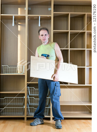 The man is engaged in assemblage of a new wardrobe 12576190