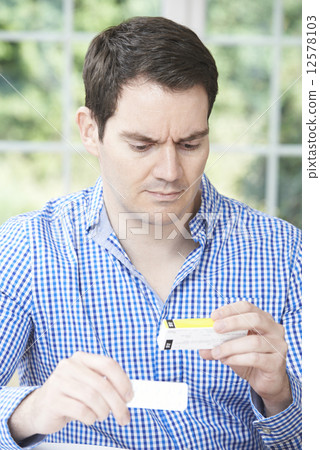 Man Reading Information On Drug Packaging Man Reading Information On Drug Packaging 12578103