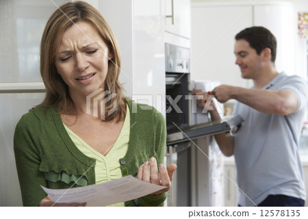 Stock Photo: Unhappy Female Customer With Oven Repair Bill