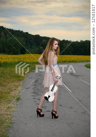 Woman stands with vilolin by country road Woman stands with vilolin by country road 12581817