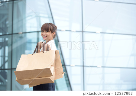 One young chinese shopaholic with her shopping buys in front of glass building mall One young chinese shopaholic with her shopping buys in front of glass building mall 12587992
