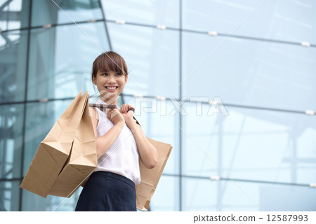 One young chinese shopaholic with her shopping buys in front of glass building mall 12587993