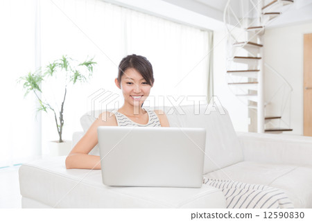 A woman using a personal computer in a room A woman using a personal computer in a room 12590830