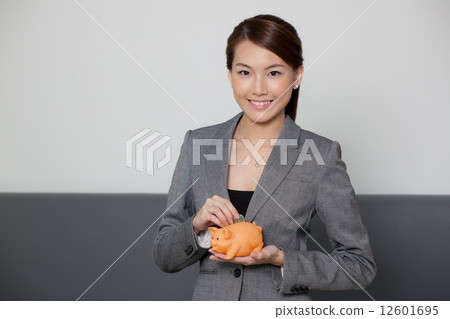 Businesswoman holding piggy bank and coin Businesswoman holding piggy bank and coin 12601695