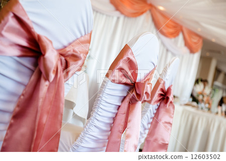 White wedding chairs with red bows indoors White wedding chairs with red bows indoors 12603502